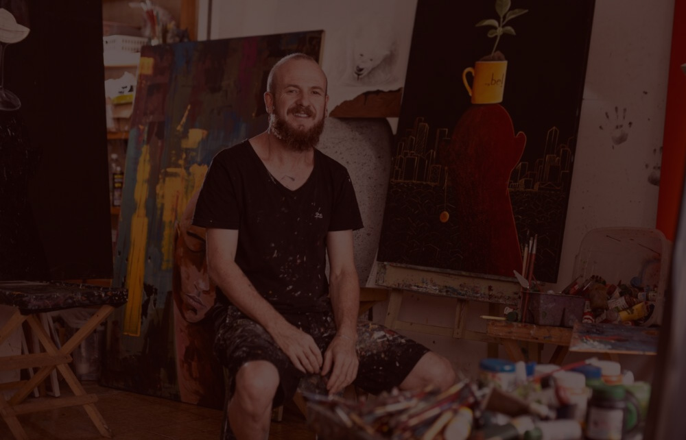 Ivaan Hansen sentado em seu ateliê de pintura