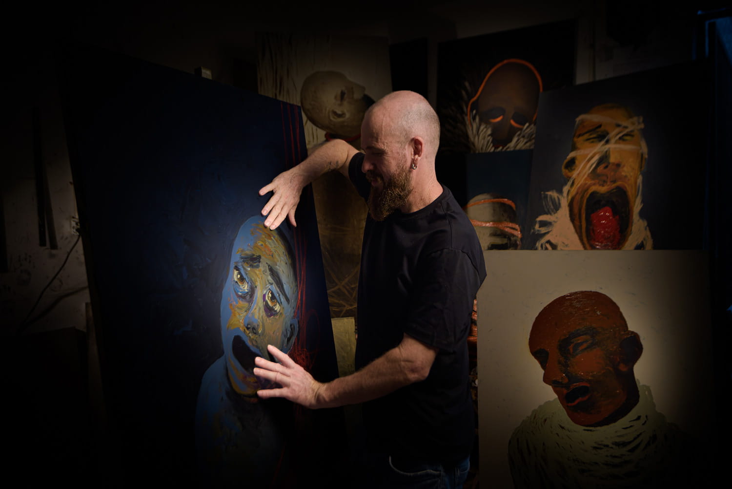 Ivaan Hansen em seu ateliê em Goiânia, entre suas pinturas de cabeças expressionistas